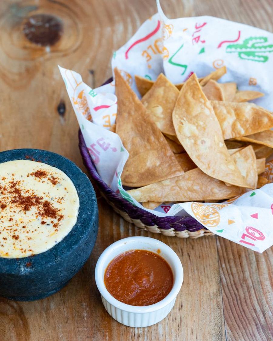 Licensed stock photograph: a stone bowl of melted queso beside a basket of tortilla chips.